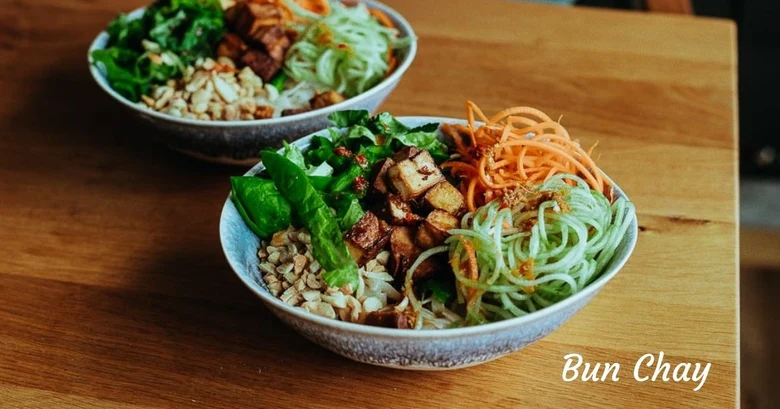 Dva misky s vietnamským veganským nudlovým salátem na dřevěném stole.
