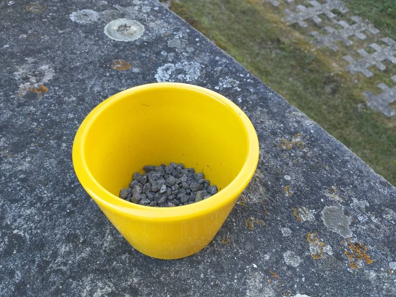 Žlutý květináč s keramzitem na kamenné desce