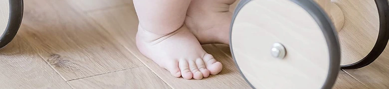 Dřevěná podlaha s dětskými nohama a hračkou