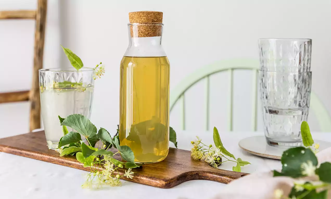 Domácí lipový sirup s květy na dřevěné desce