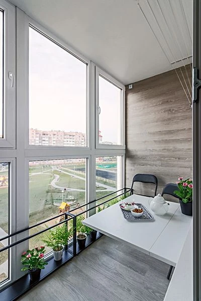 Moderní lodžie s rostlinami a jídelním setem pro relaxaci.