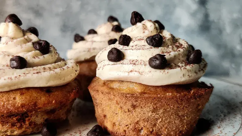 Tři čokoládové muffiny s krémem na talíři.