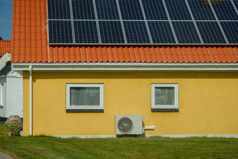 Žlutý dům s tepelným čerpadlem a solárními panely