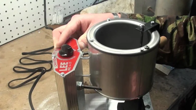 Osoba používá elektrický topič olova s bezpečnostním štítkem.