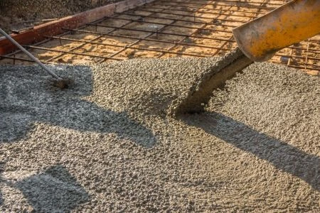 Nalévání betonu na ocelovou mřížku při stavbě.