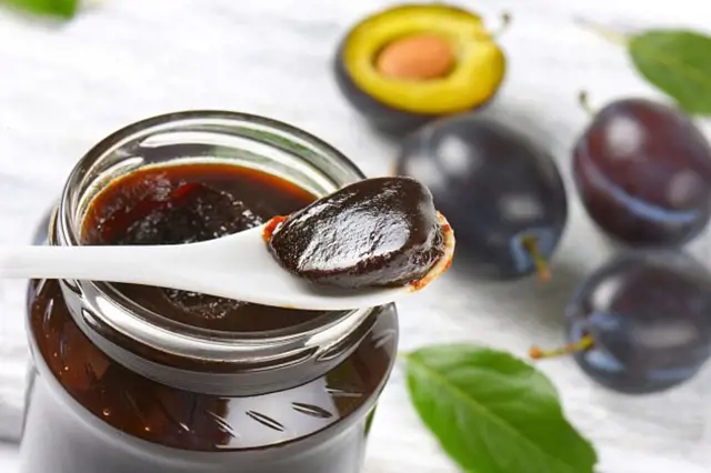 Švestková marmeláda v sklenici s čerstvými švestkami