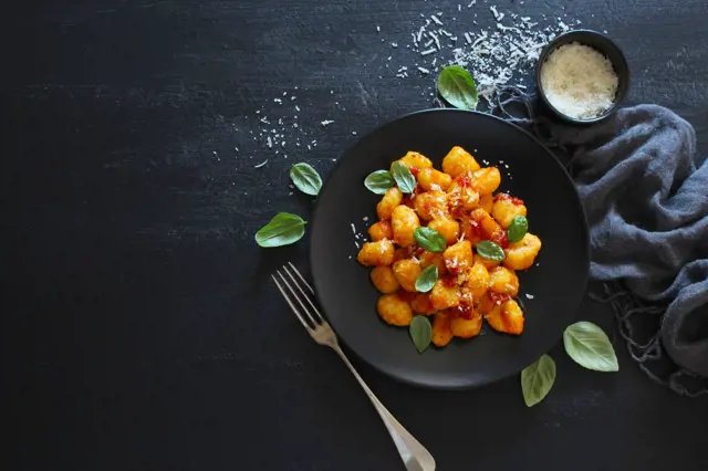Gnocchi s rajčatovou omáčkou na černém talíři