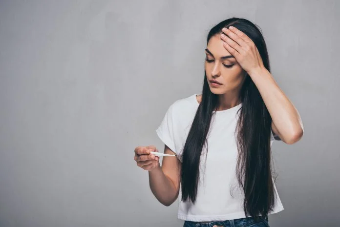 Žena s teplometrem, má vysokou teplotu