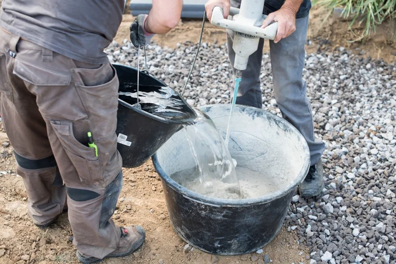 Dva dělníci smíchají beton v sudu