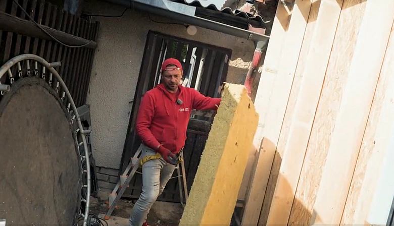 Muž instaluje izolaci na fasádu domu