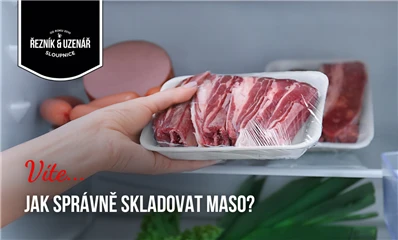 Rukou se drží balení syrového masa v lednici.