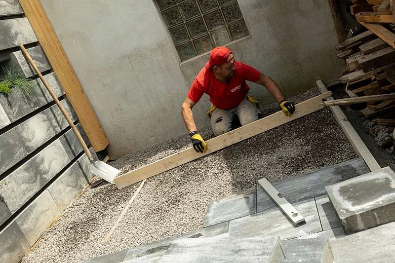 Stavebník položí štěrkový chodník vedle budovy