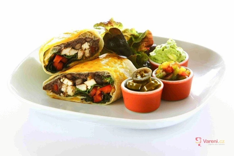Mexický burrito s fazolí, sýrem a zeleninou na bílém talíři.