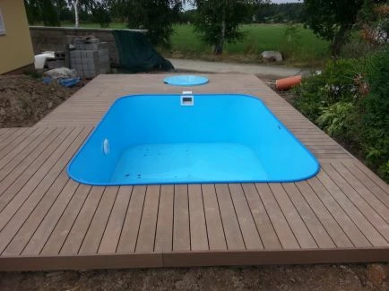 Modrý bazén v dřevěné terase na zahradě