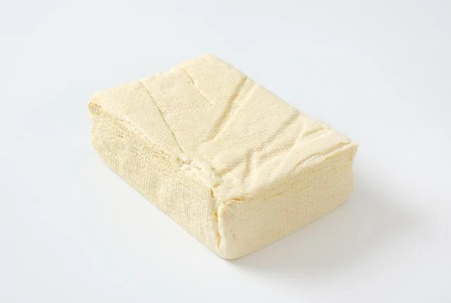 Kus bílého tofu na světlém pozadí.