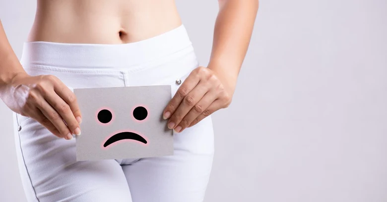 Žena drží kartičku s smutným emotikonem před břiškem.