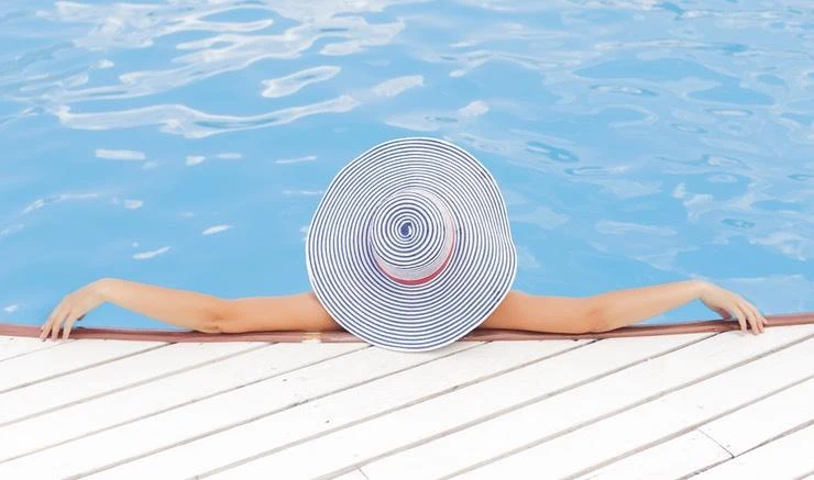 Osoba v koupališti s širokou sluneční čepicí relaxuje.