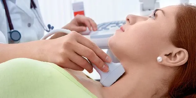 Lékař provádí ultrazvukové vyšetření štítné žlázy pacientovi.