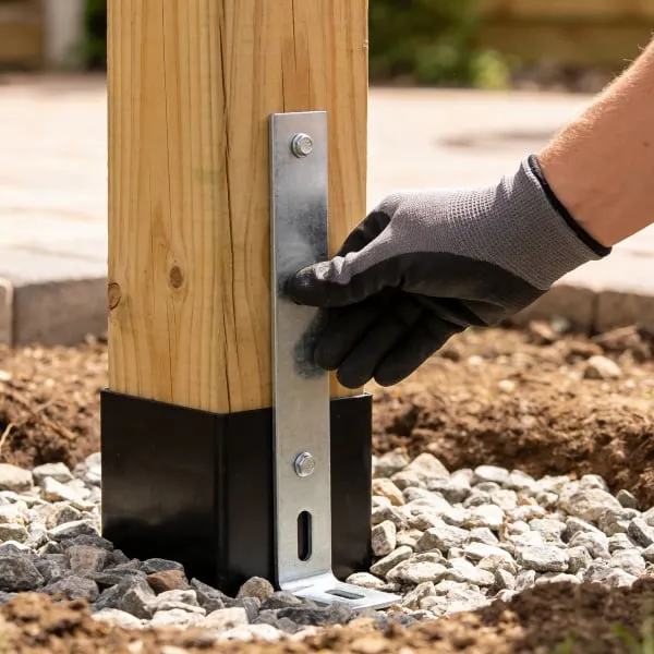 Ruční instalace kovového držáku na dřevěný sloup pergoly.