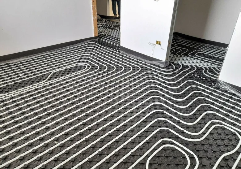 Instalace podlahového topení s hadicemi na izolační desky.