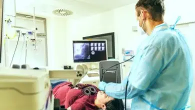 Lékař vyšetřuje pacienta v nemocničním prostředí s lékařskými přístroji.
