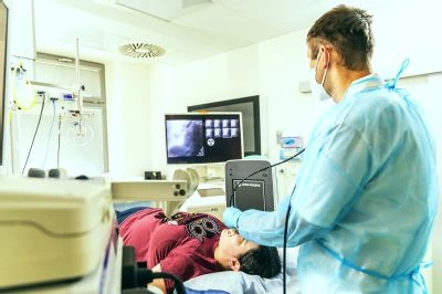 Lékař vyšetřuje pacienta v nemocničním prostředí s lékařskými přístroji.
