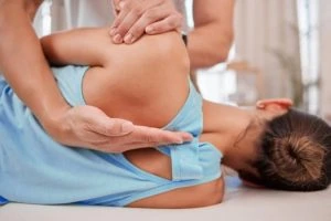 Terapeut provádí osteopatickou manipulaci na zádech pacienta.