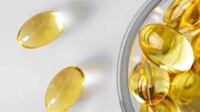 Žluté želatinové tobolky s vitamínem D v skleněné mísce.