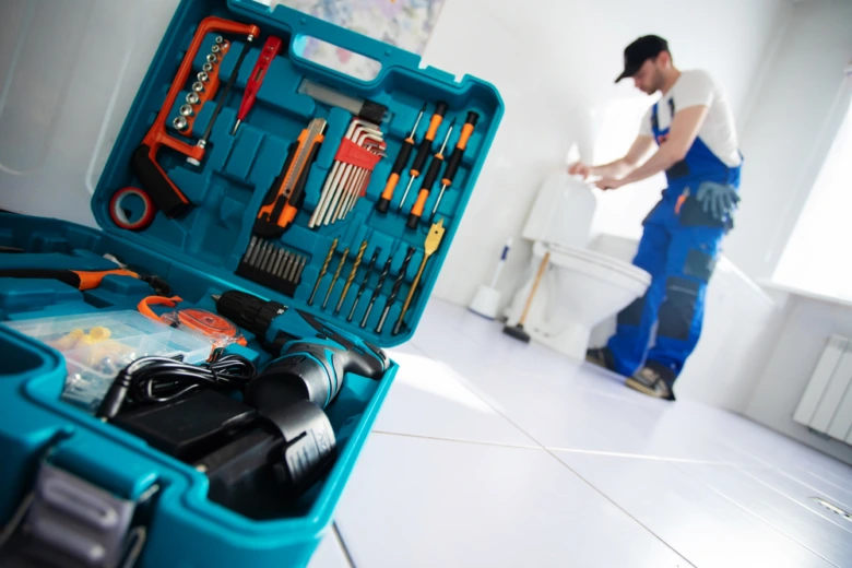 Plumber with tools fixing toilet