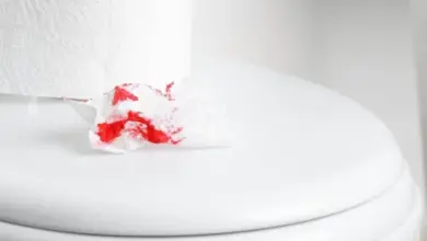 Kus znečištěné červenou krví toaletního papíru na víku WC.
