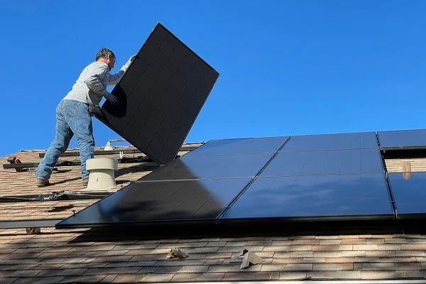 Montáž fotovoltaických panelů na střechu domu.