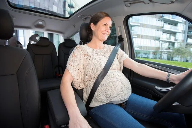 Těhotná žena řídí auto s bezpečnostním pásem přes břicho.