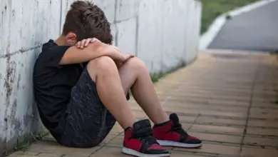 Smutný chlapec sedí u zdi – příznaky puberty.