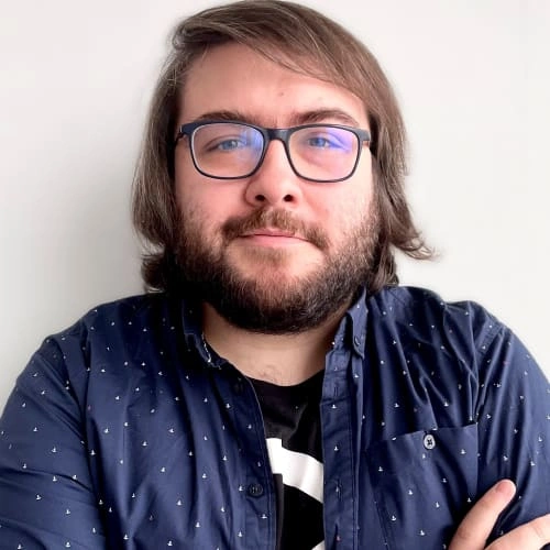 Muž s brýlemi a vousy na bílém pozadí.