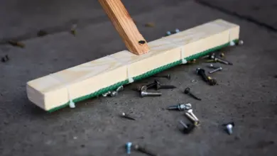 Dřevěný nástroj s hřebíky a šrouby na betonové podlaze.