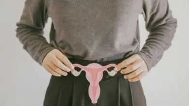 Žena drží model ženských pohlavních orgánů před pasem.