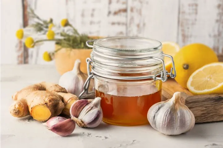 Sklenice medu s česnekem, zázvorem a citrony pro přírodní léčbu.