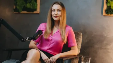 Žena v růžovém tričku sedí u mikrofonu pro rozhovor.