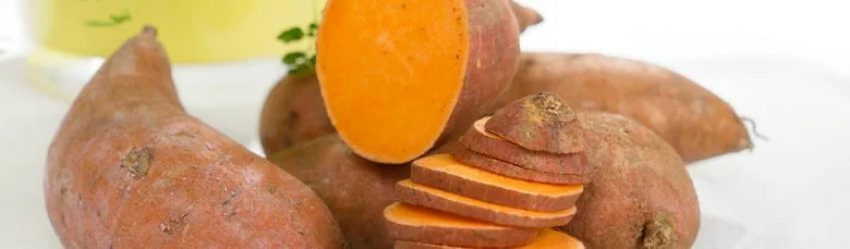 Kus batátové povijnice s řezem ukazující oranžovou dužinu.