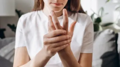 Žena drží ruku v bolesti kvůli revmatickému onemocnění.