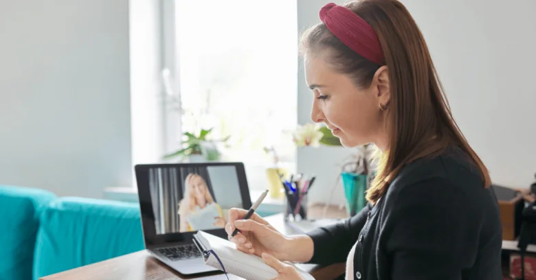 Žena píše poznámky během online kurzu na notebooku.