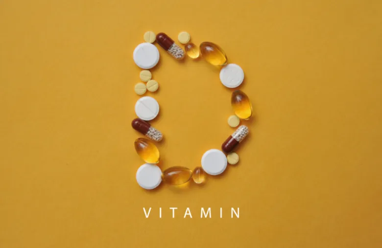 Různé vitamíny tvarující písmeno D na žlutém pozadí.