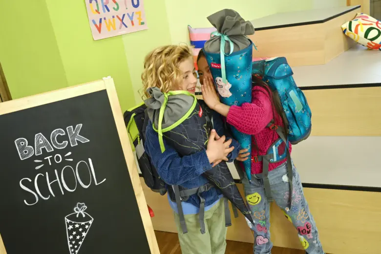 Děti s batohy plnými školních potřeb v třídní místnosti.