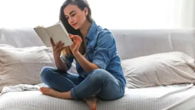 Žena sedí na gauči a čte knihu.