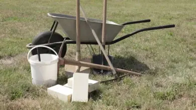 Kolo s kbelíkem, lopatou a cihly na trávníku pro stavbu ohniště.