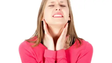 Žena s bolestí hrdla drží si ruce kolem krku.