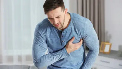 Muž v modrém tričku drží hrudník kvůli bolesti.