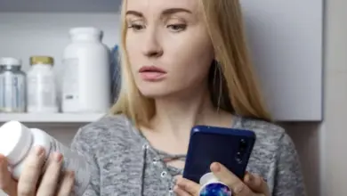 Žena zkoumá doplňky stravy a hledá informace na mobilu.