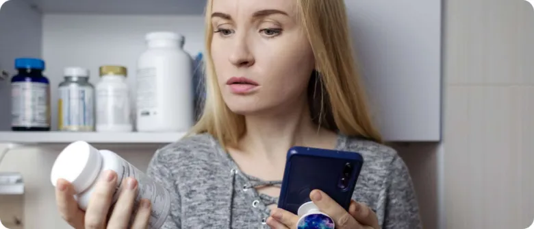 Žena zkoumá doplňky stravy a hledá informace na mobilu.