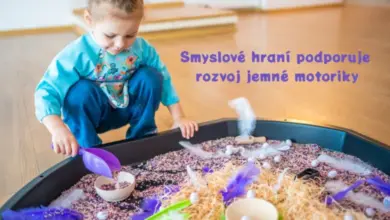 Dítě hraje s jemnou motorikou v hračičce plné písku a peří.